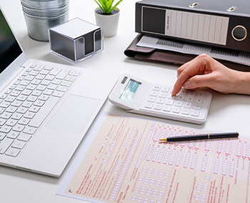 A person using a calculator while filling out a form