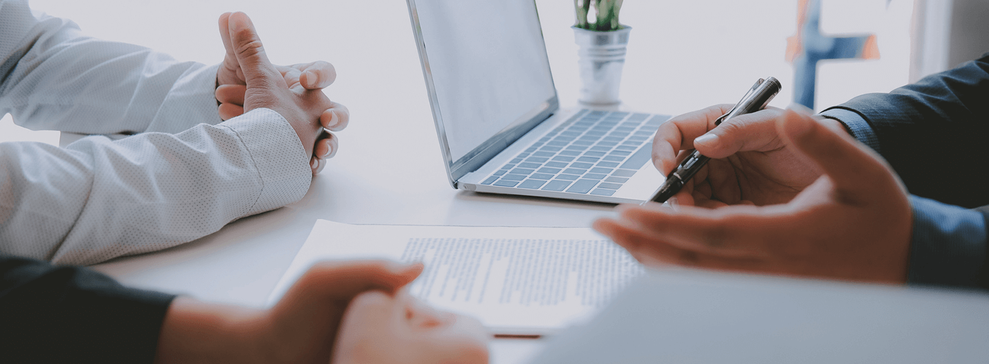 Highlighting words on a piece of paper with a laptop on the desk