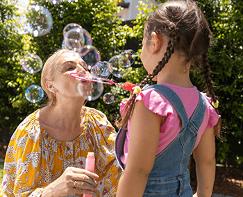 Old lady blowing soap bubbles with a child in front of her