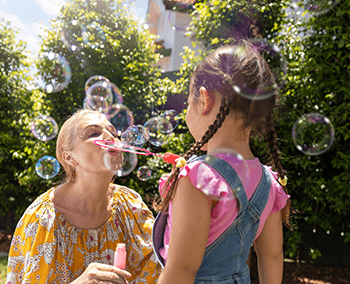Old lady blowing soap bubbles with a child in front of her